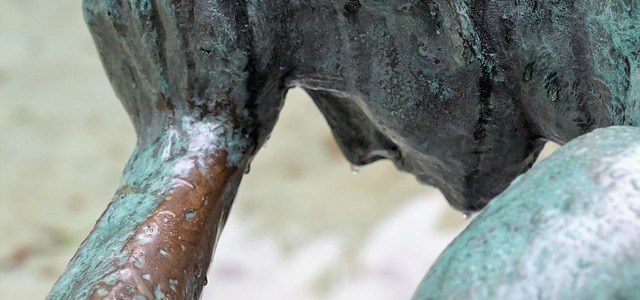 Statue of person holding drooping head with one hand